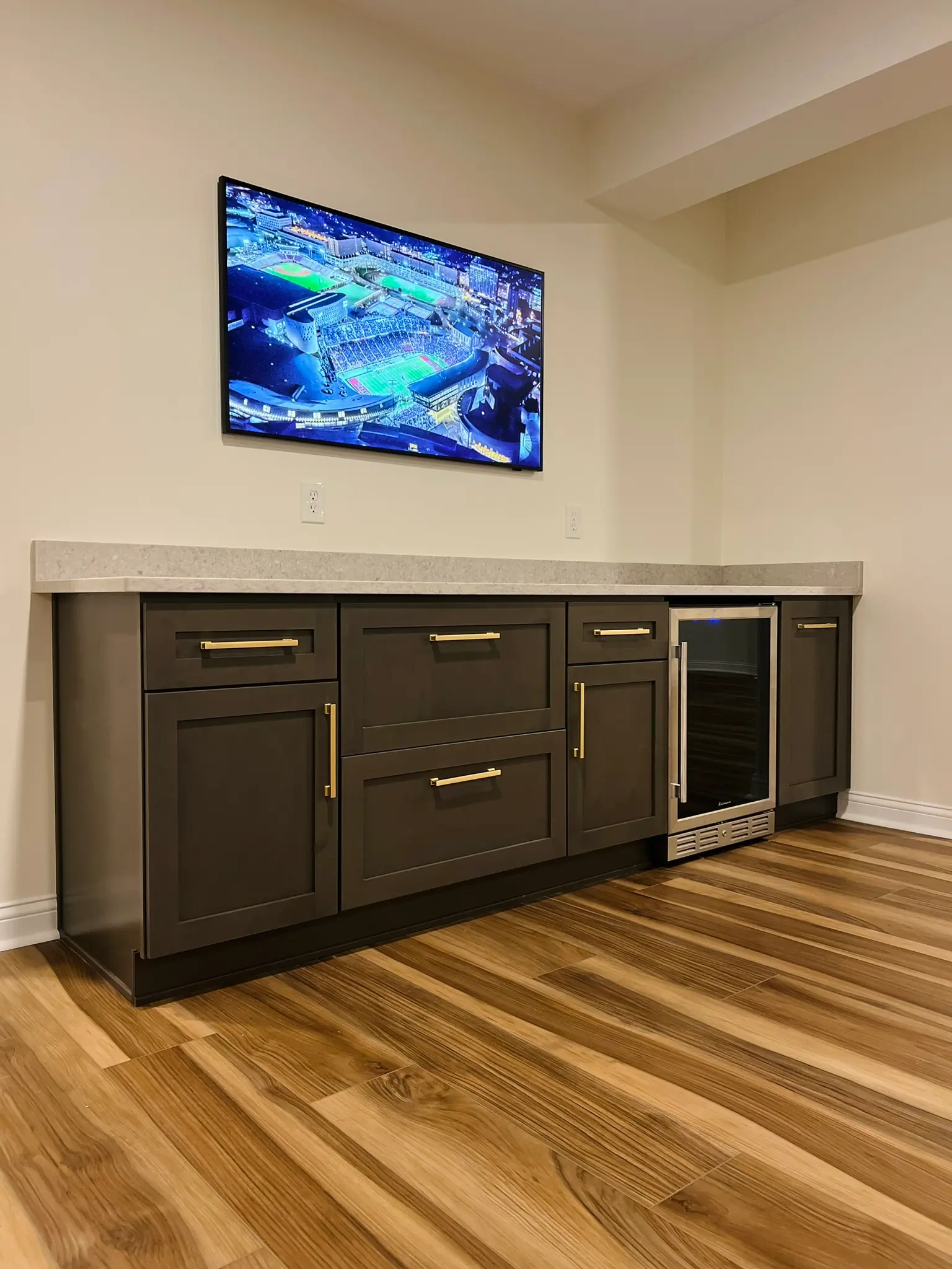 Basement wet bar with espresso shaker cabinets, quartz countertop, beverage fridge, and gold hardware