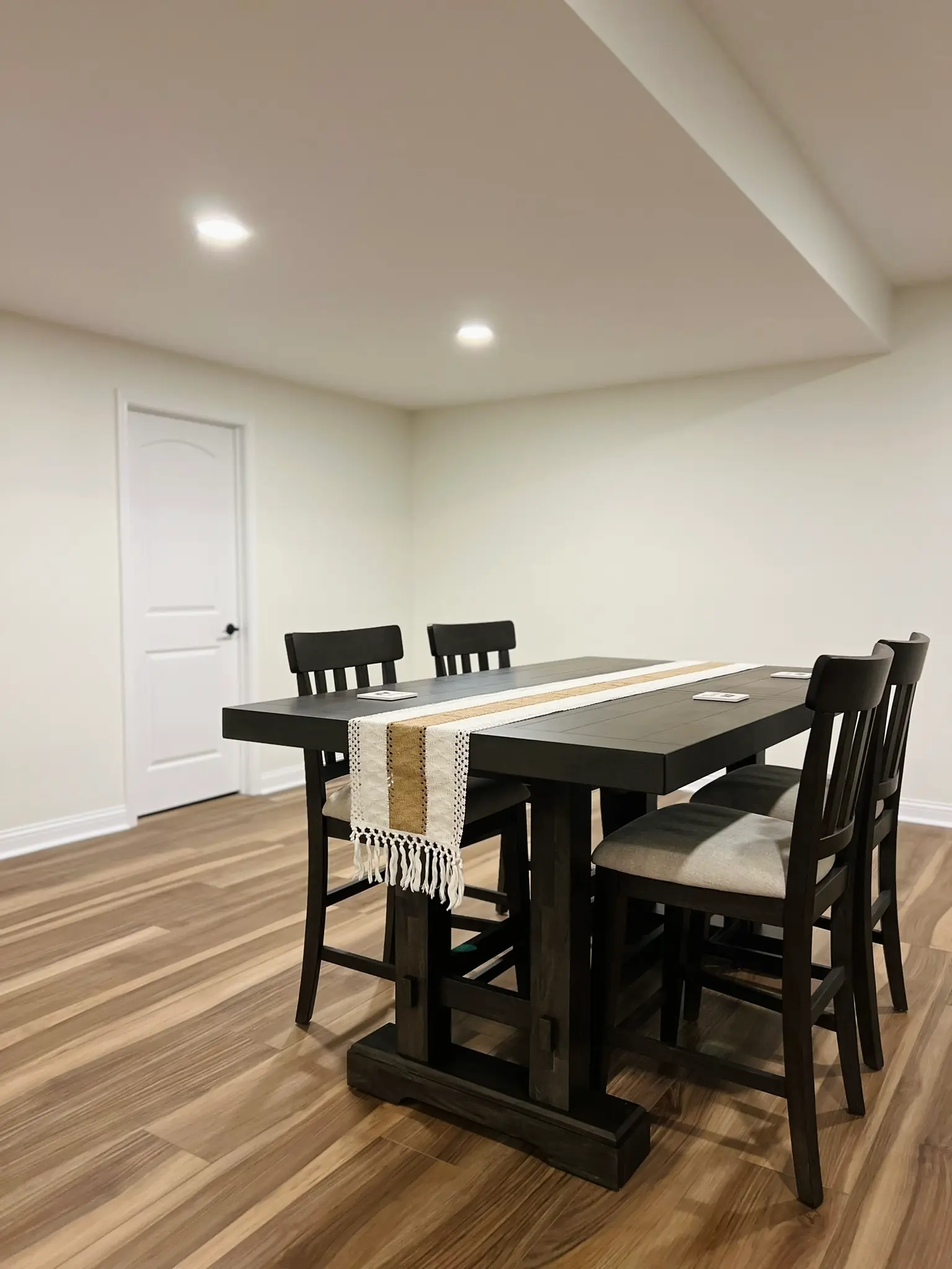 Finished basement dining area with pub-height table, dark chairs, and hardwood LVP flooring