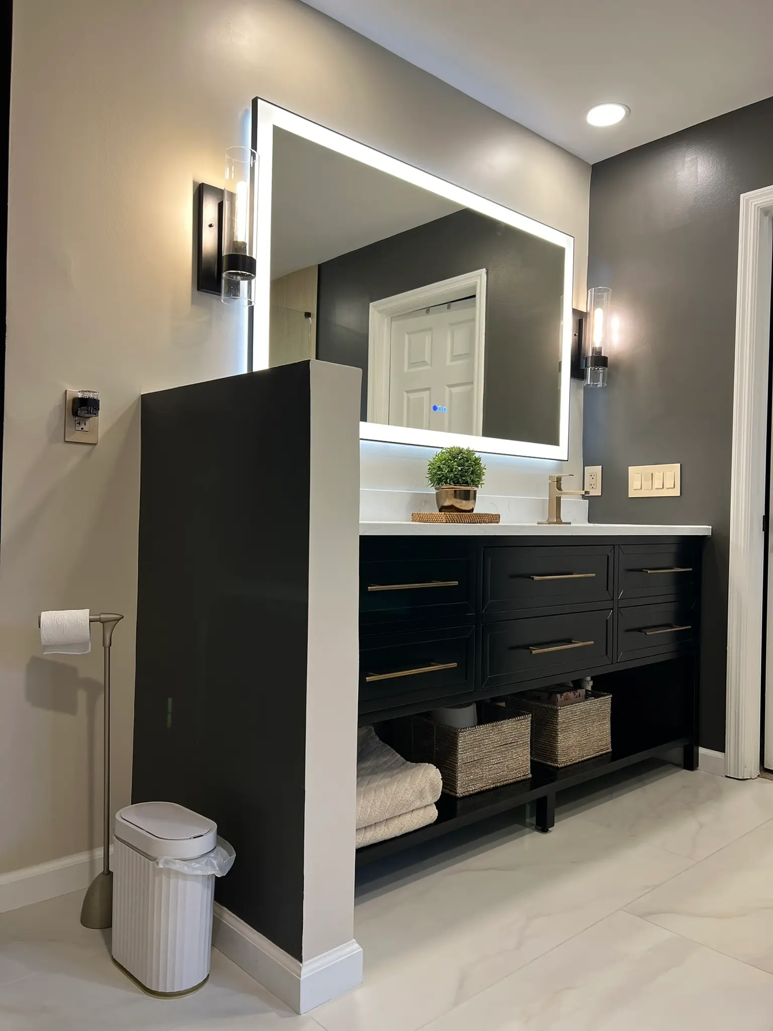Modern bathroom with matte black vanity, LED backlit mirror, and open shelving