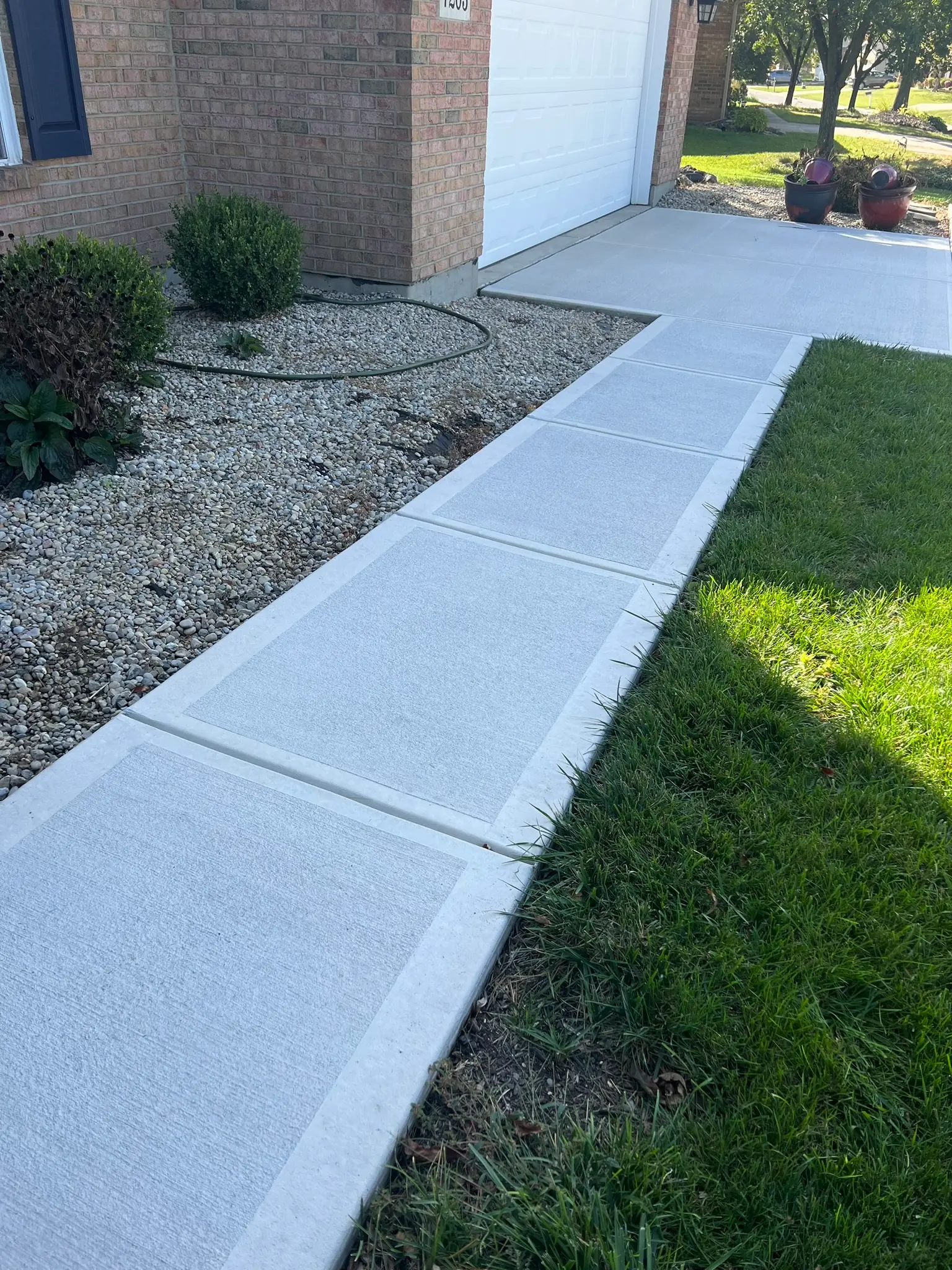 New concrete front walkway and garage approach on brick home