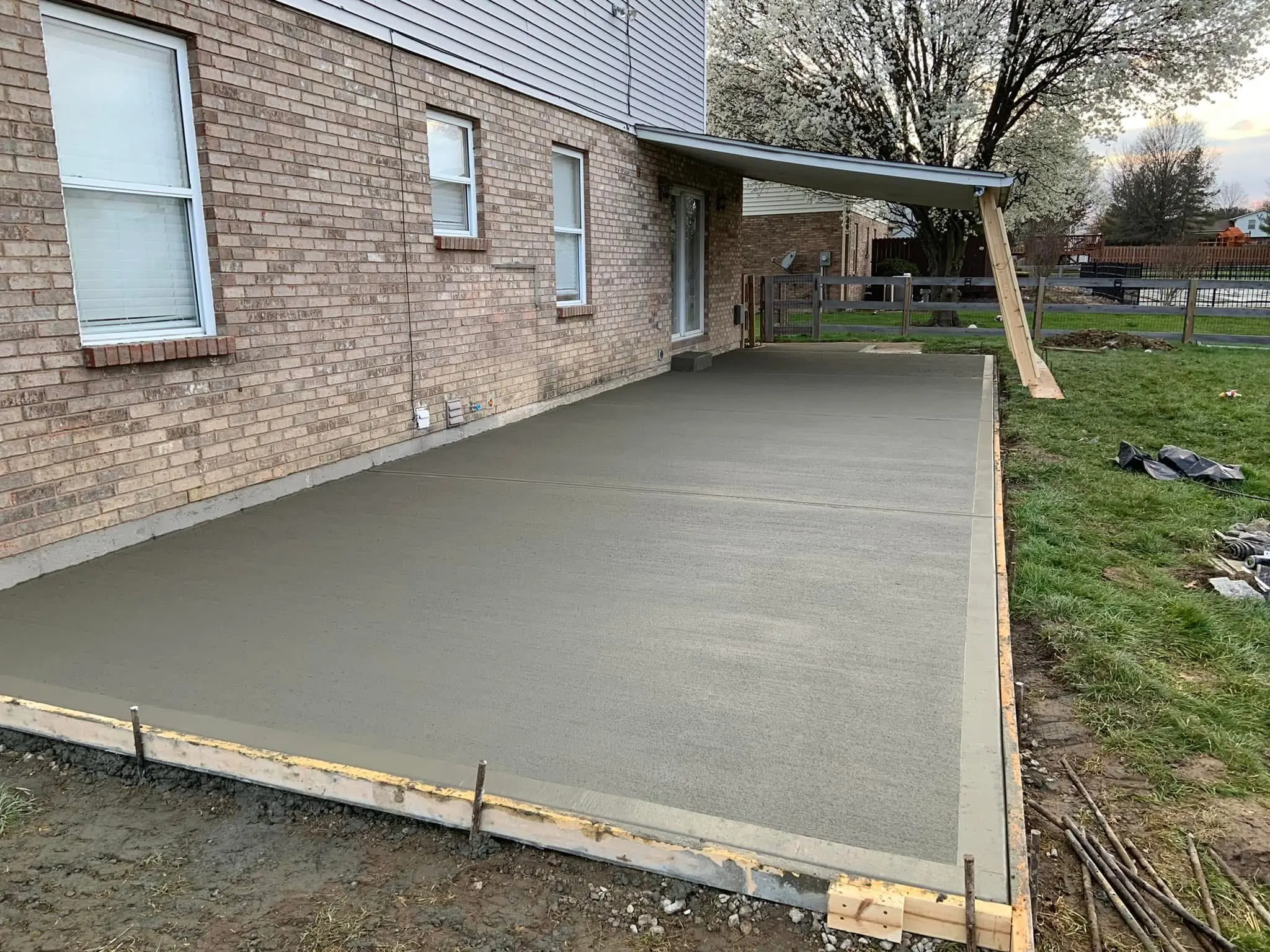 Fresh-poured concrete patio slab next to brick home