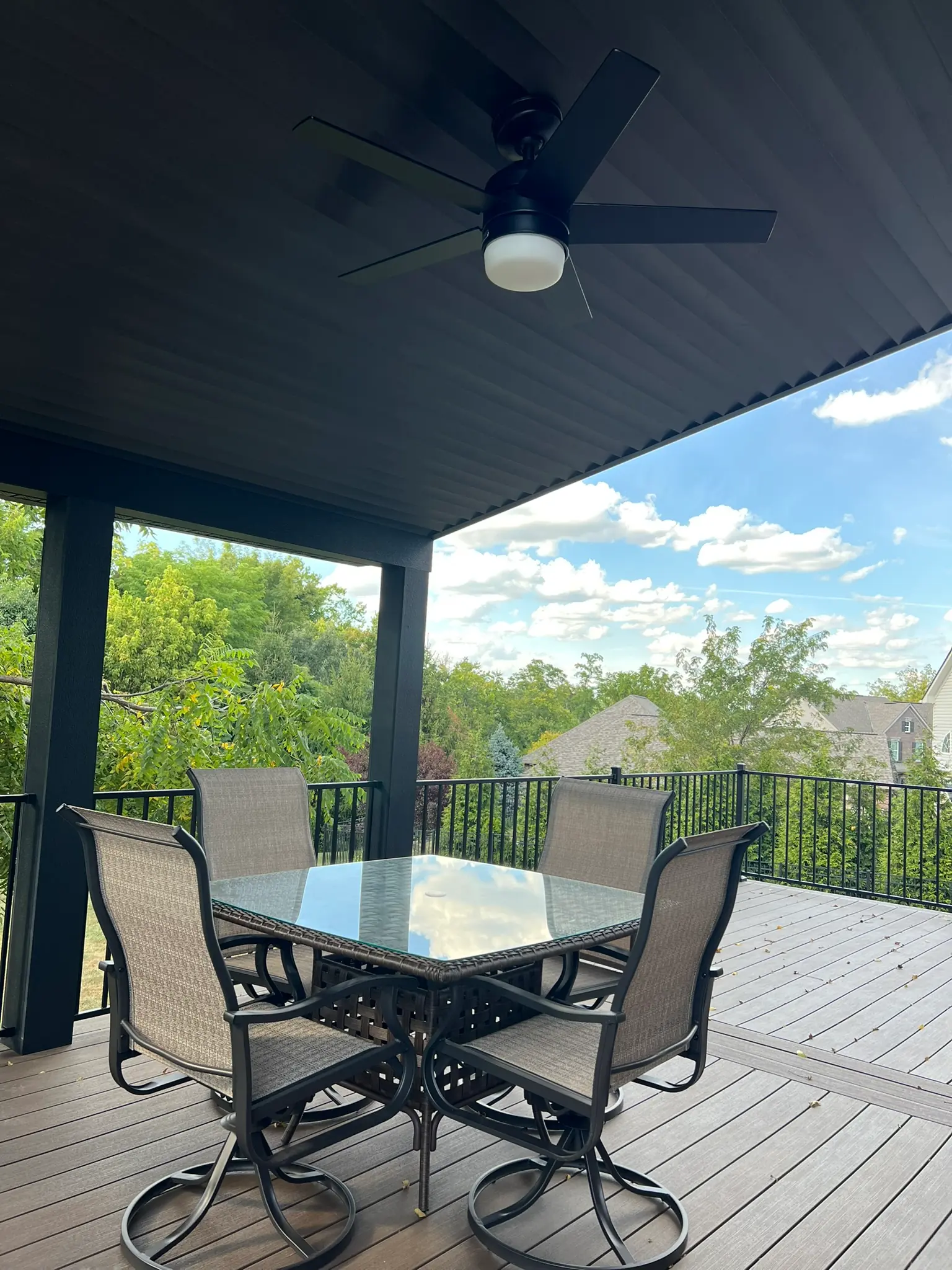 Covered deck with pergola, ceiling fan, and outdoor dining set with black composite railing