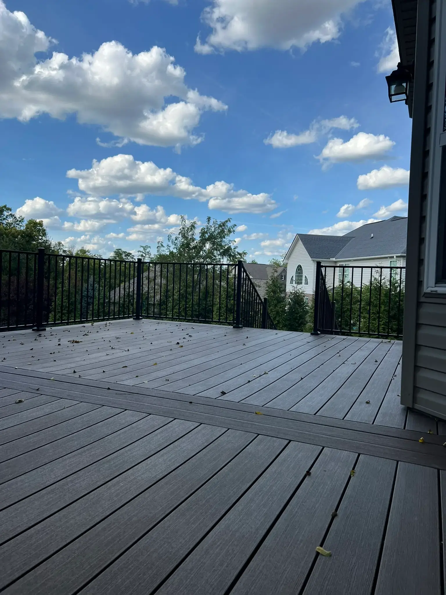 Elevated gray composite deck with black aluminum railing overlooking backyard