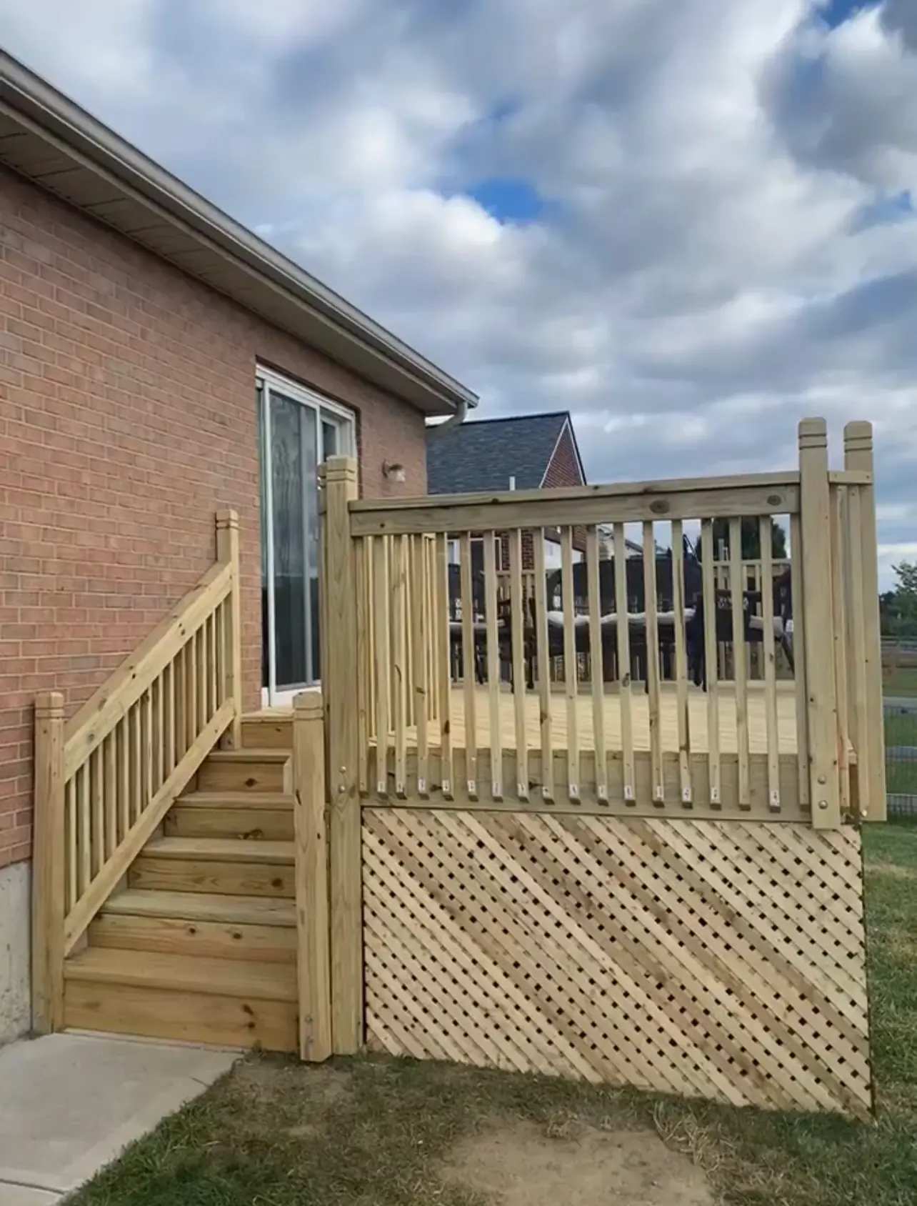 Pressure-treated wood deck with lattice skirting and stairs on brick home