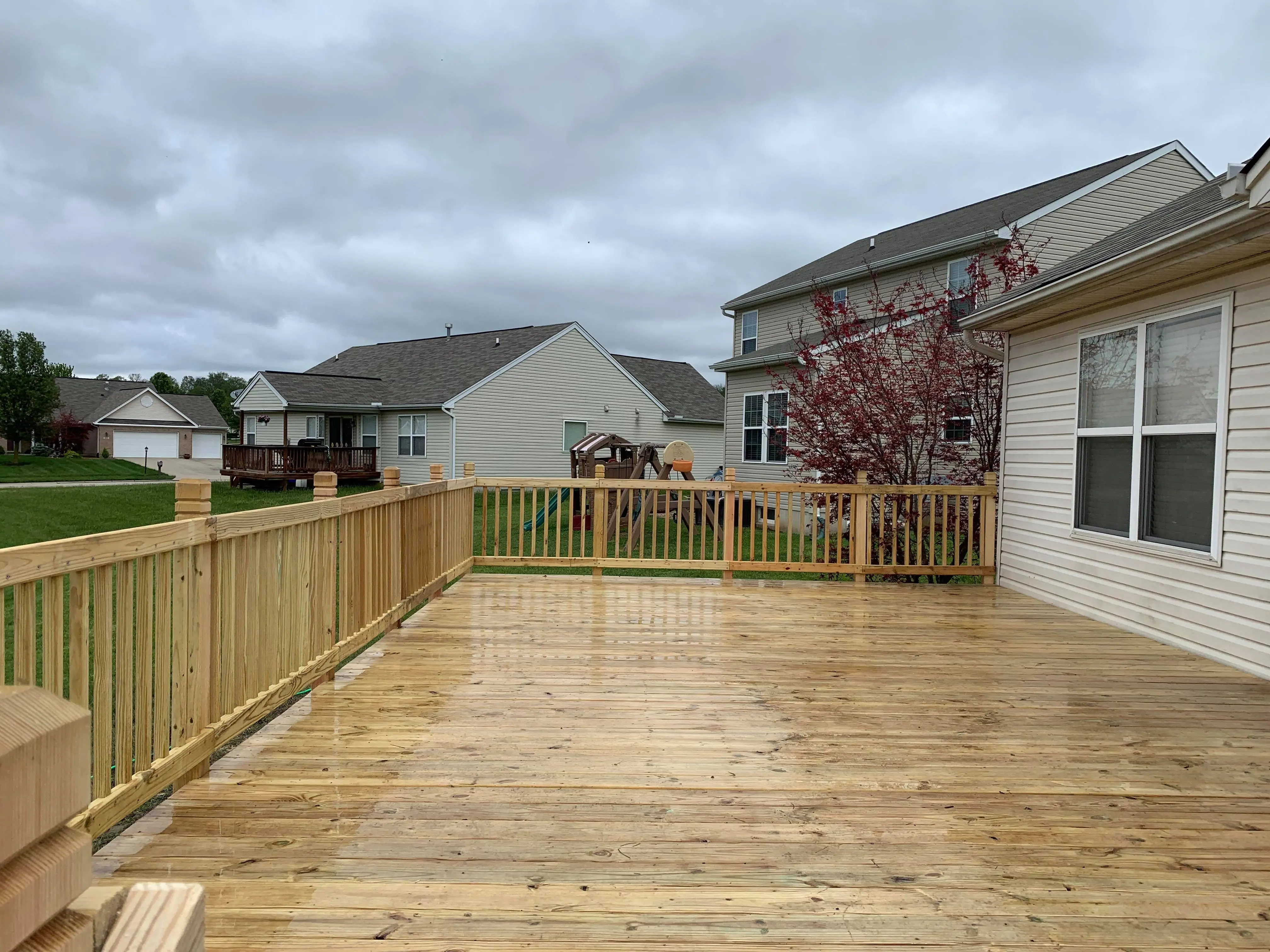 New pressure-treated wood deck with spindle railing and wide backyard view