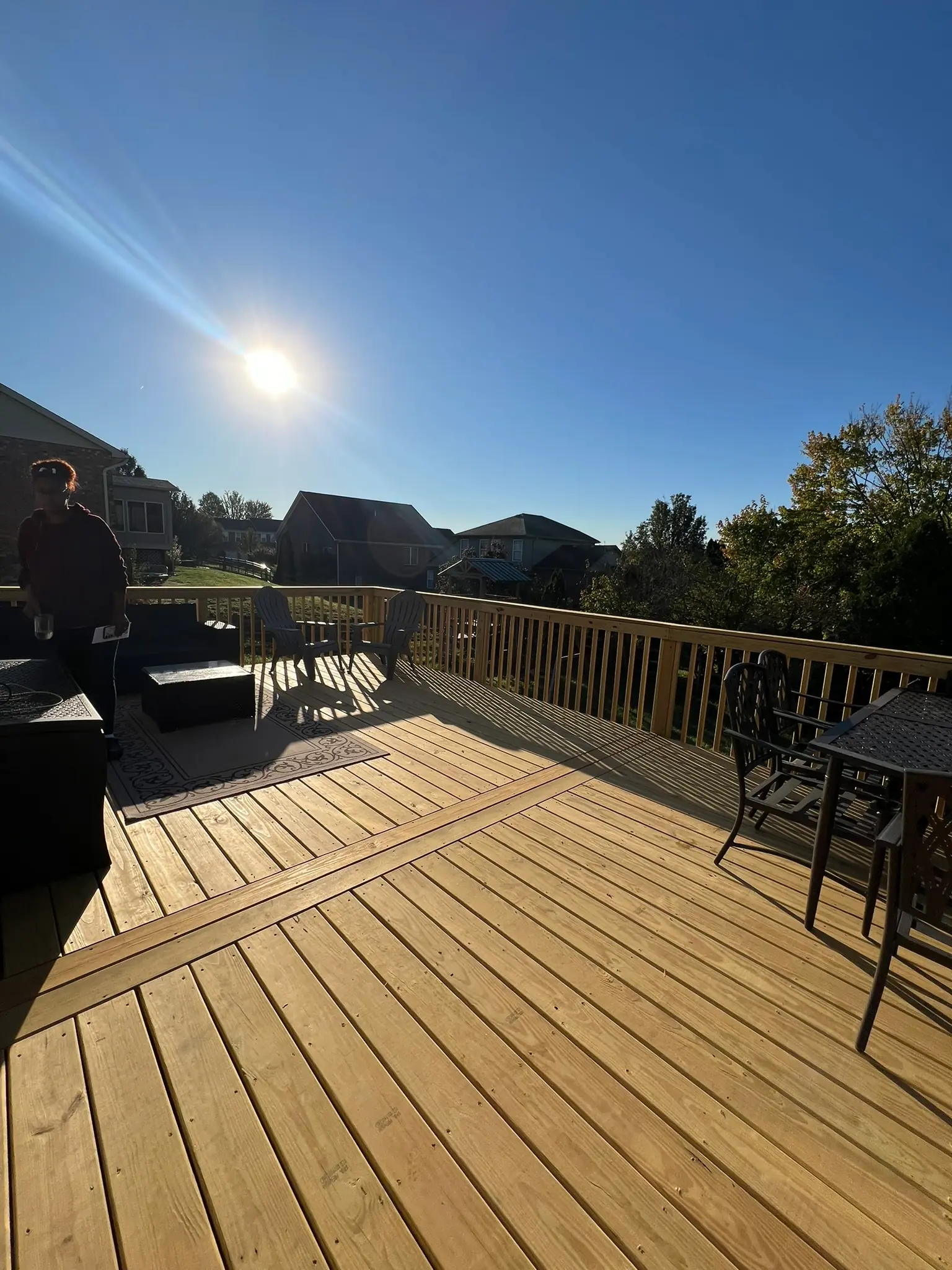 Pressure-treated wood deck wide angle view with wood railing and backyard