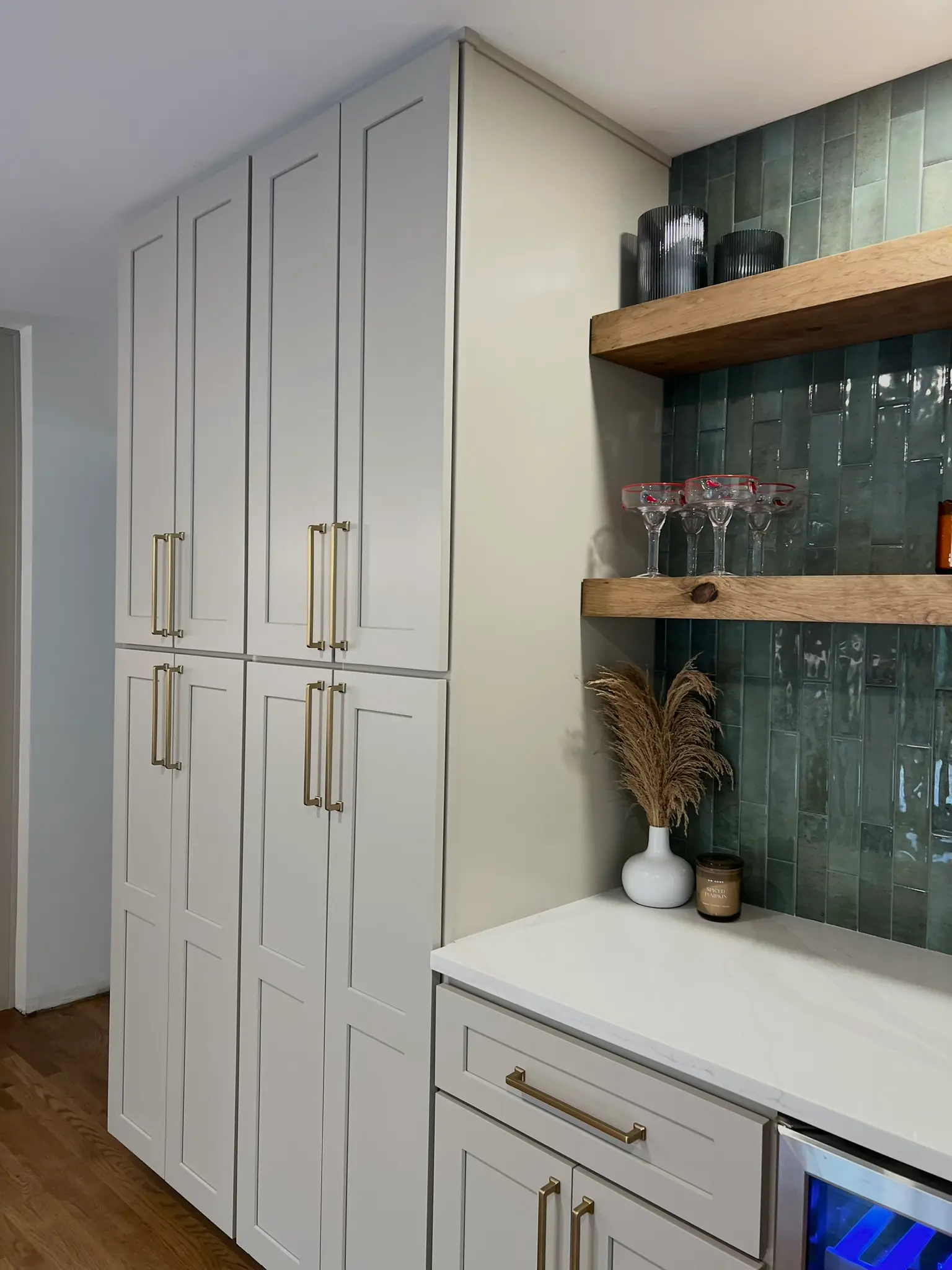 White pantry cabinetry with built-in bar nook featuring teal zellige tile backsplash, oak floating shelves, and wine cooler